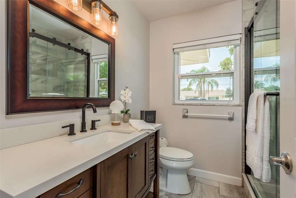 Bathroom 1 has undergone a tasteful renovation, featuring granite countertops, an updated vanity, a luxurious walk-in shower, and sleek ceramic floors, epitomizing modern elegance and comfort.