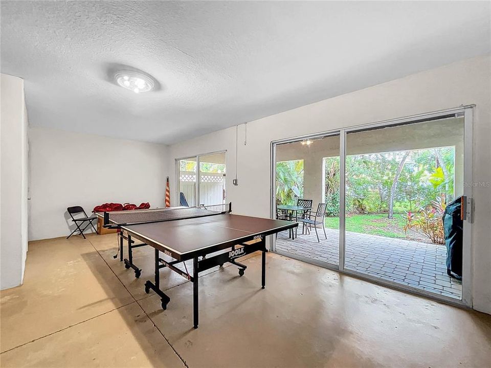 Ground level recreation room with ping pong table and outside covered paver patio