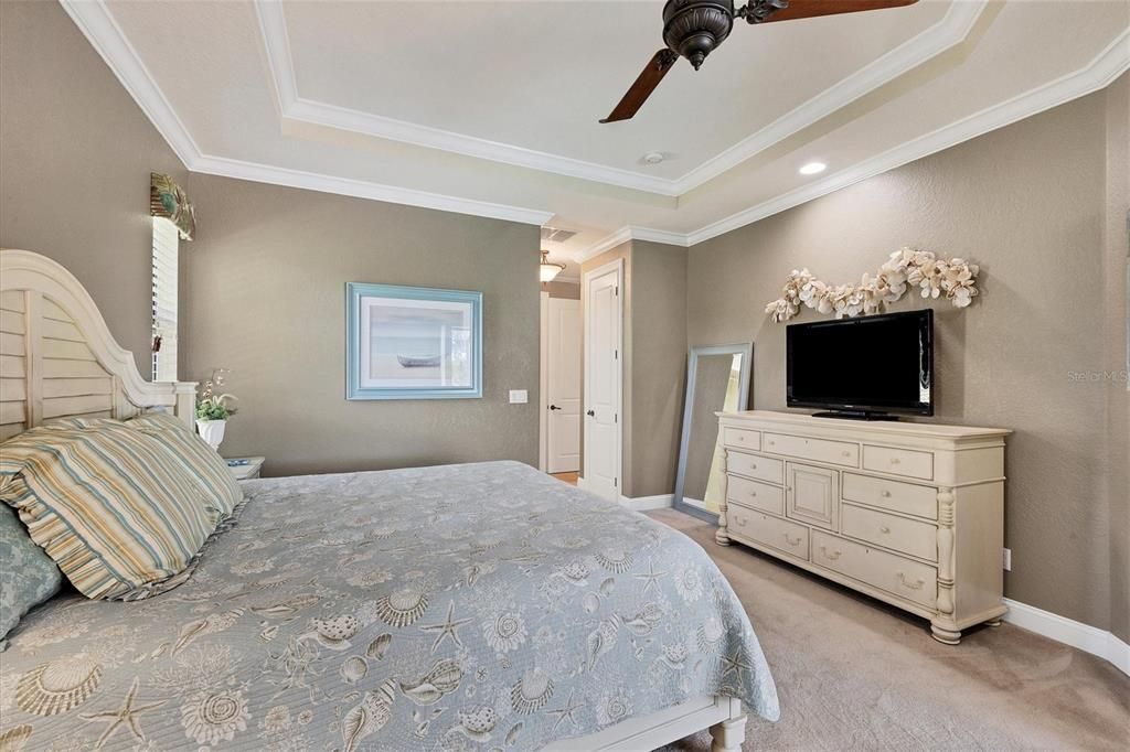 Spacious primary bedroom featuring stunning tray ceilings