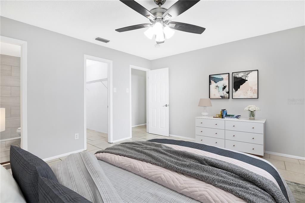 Virtually staged photo - primary bedroom with walk-in closet and ensuite bathroom