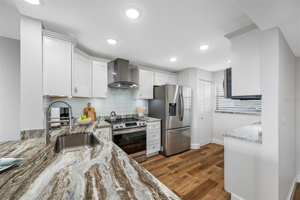 Kitchen with range and gourmet hood, all stainless steel appliances.