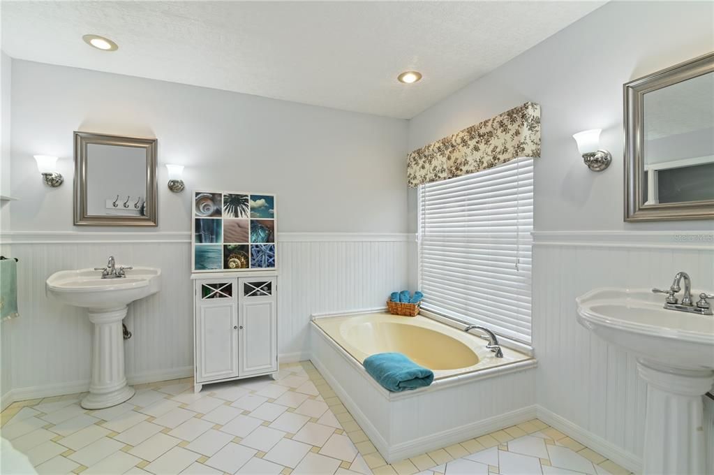 The primary bathroom has two pedestal sinks, a garden tub, a separate shower, and a water closet.
