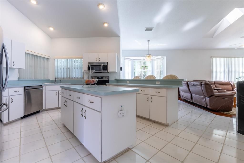 The Kitchen has a Reach-in Pantry, Kitchen Island, spacious counters, windows, and
