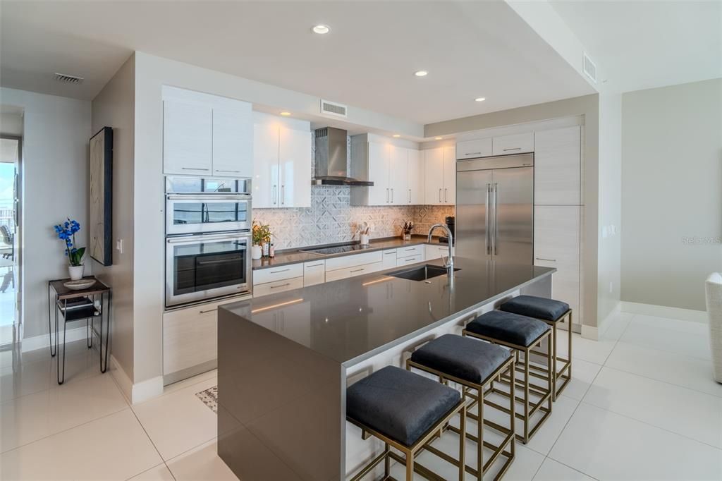 Gourmet kitchen features state-of-the-art stainless steel appliances, stone countertops, custom backsplash, with under cabinet lighting