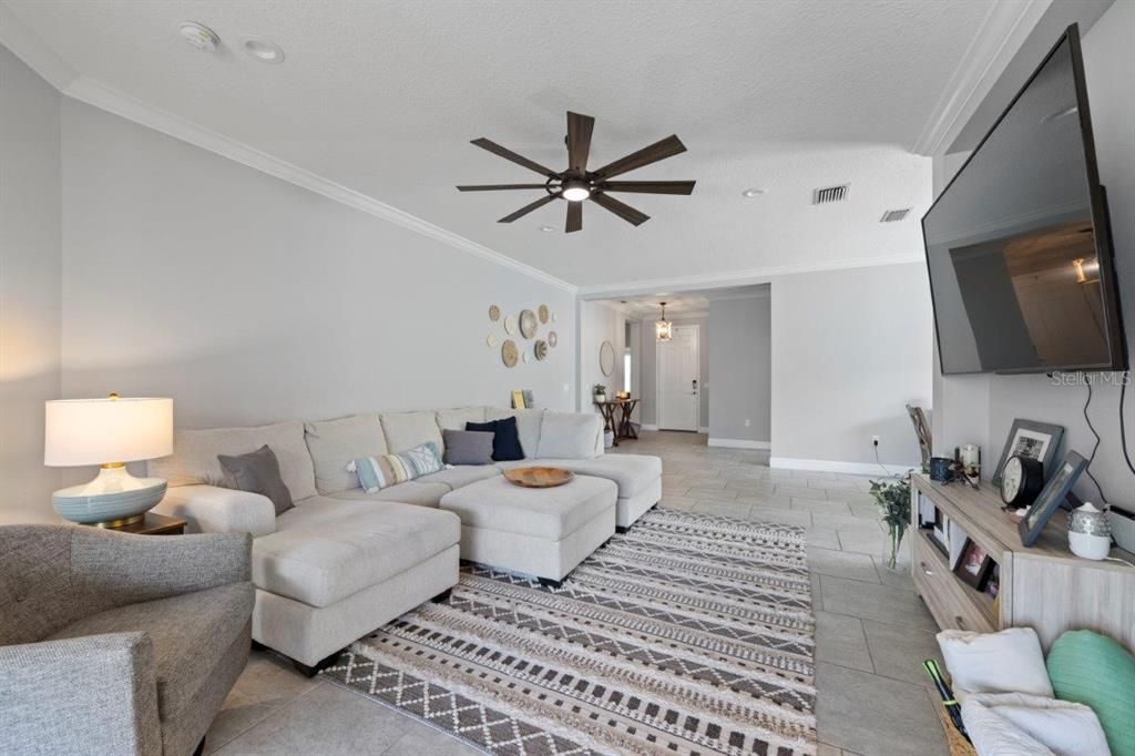 Living room featuring custom built-ins, modern staggered tile flooring, and crown molding.