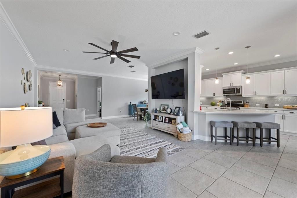 Living room featuring custom built-ins, modern staggered tile flooring, and crown molding.