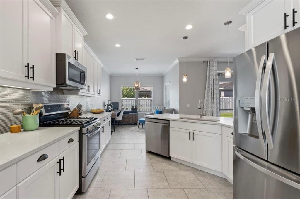 Spacious kitchen featuring ample cabinetry, stainless steel appliances, and a stunning backsplash.