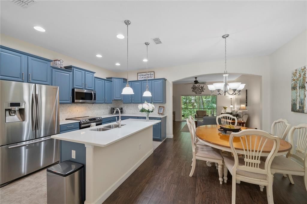 Kitchen is open to the dining room that features wood-look porcelain tile floors