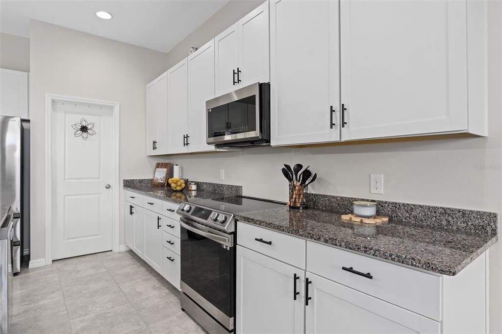 a great view of the beautiful kitchen shaker cabinets wrapped in granite and stainless steel appliances. What is behind that door!