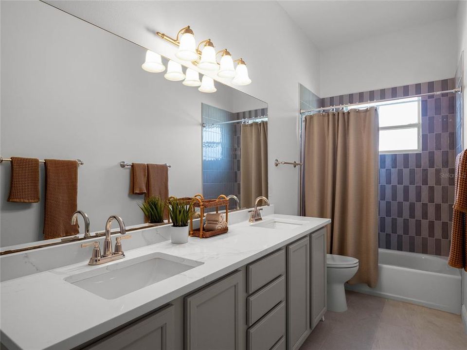 2nd Level Jack and Jill Bathroom with elevated plumbing fixtures, solid surface quartz counters and designer tile.