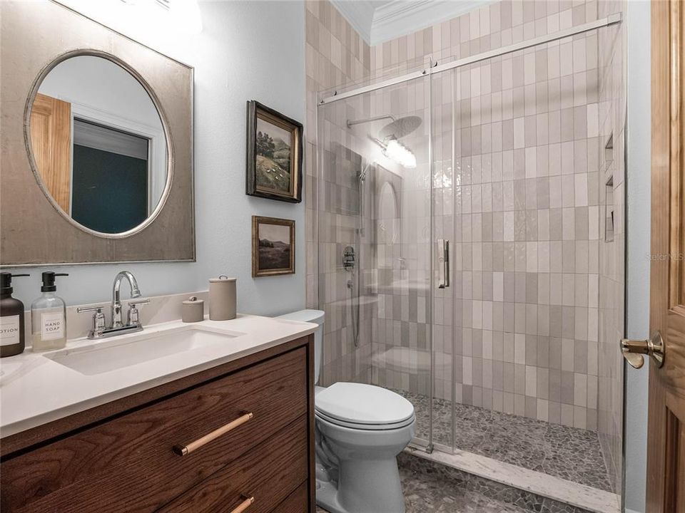 Secondary bathroom with custom tilework, designer fixtures and glass shower doors.