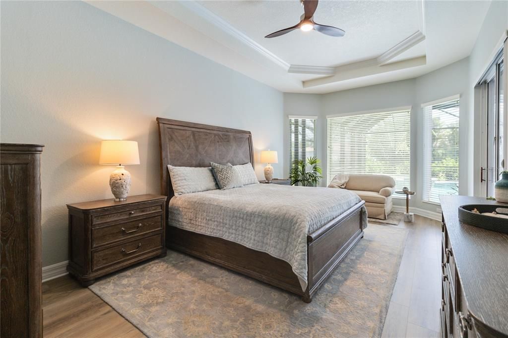 Primary suite with high double tray ceilings, crown molding and luxury vinyl planks installed. Relax in your private retreat in the light filled sitting area right next to your very own private entrance to the lanai