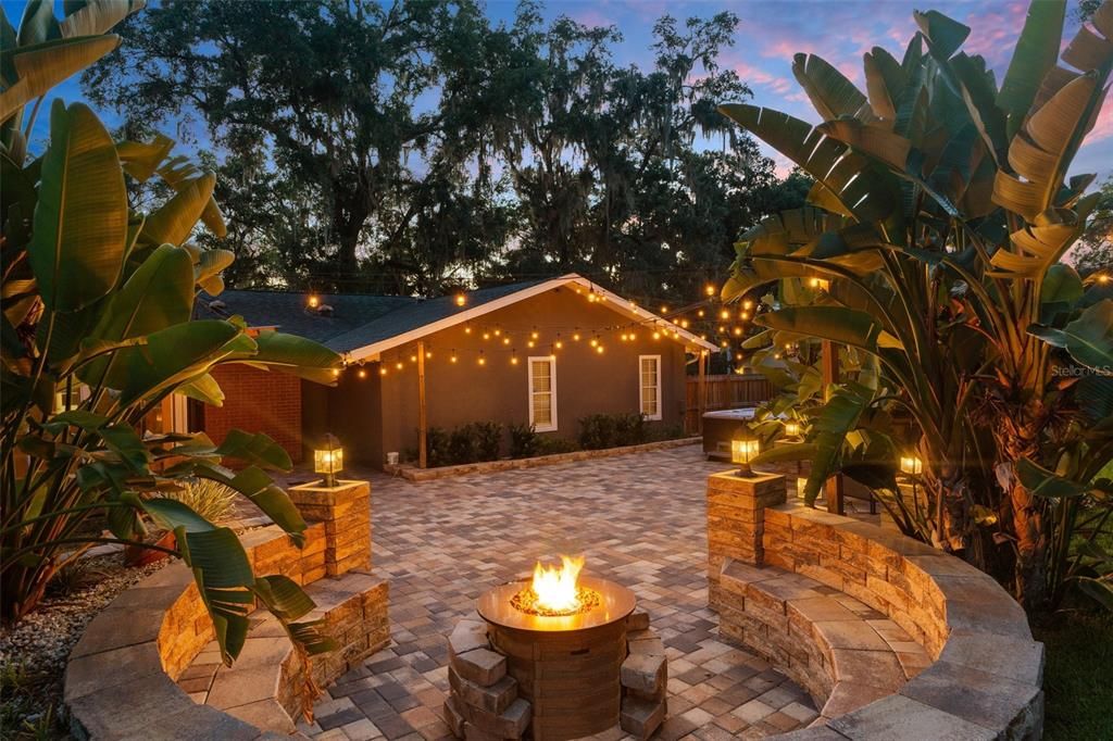 Propane fire pit and cafe lights make for a moody outdoor living space in the evening.