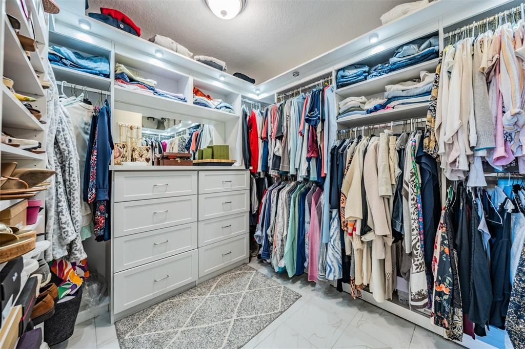 Primary walk in closet with custom built in shelving system