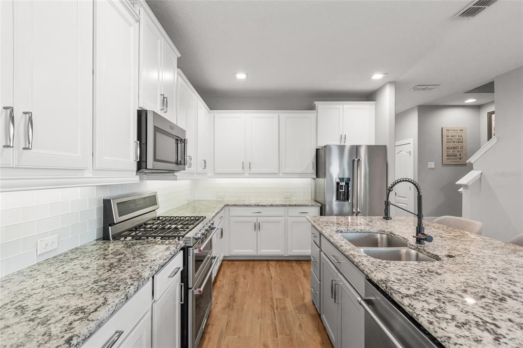 Kitchen with white 42" cabinets, granite counters and all appliances remain! Luxury vinyl plank flooring throughout the first floor!
