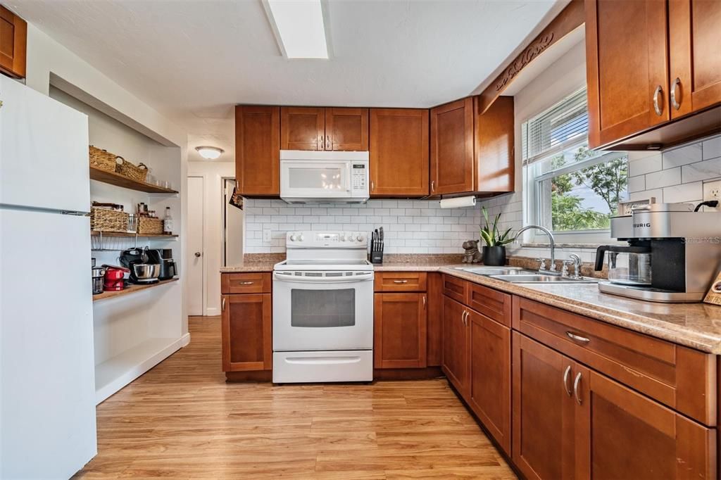 kitchen features stylish wood shaker-style cabinets, subway tile backsplash, Formica countertops and built-in storage shelves.