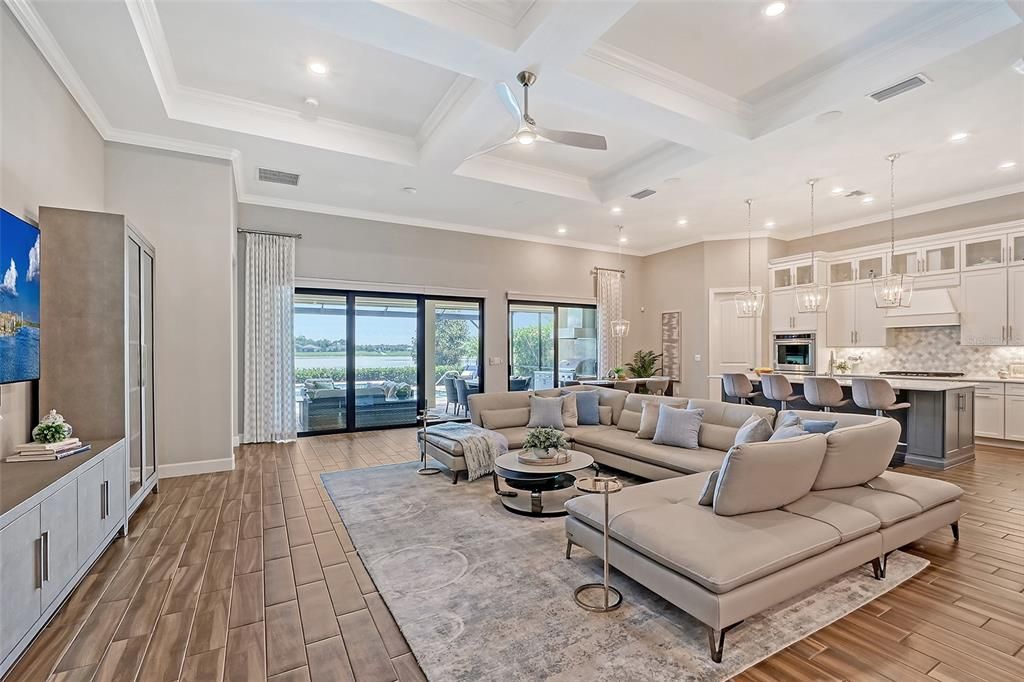 Great room with coffered ceiling, porcelain plank flooring, formal and casual dining spaces