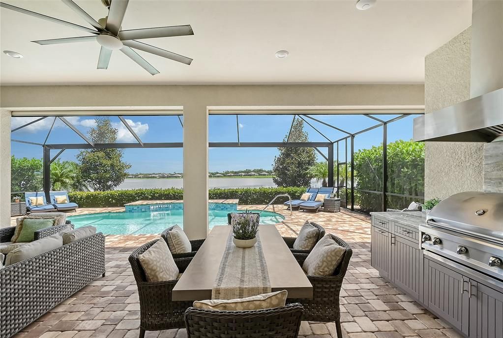 Outdoor kitchen with fridge, sink, grill, vent hood, granite counter top and backsplash