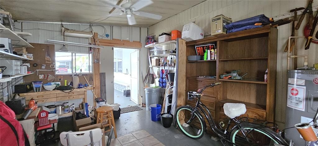 Storage/Utility room includes rear & front entry, windows, electricity, ceiling fan, washer/dryer, shelves, workbench, electric water heater, washer, dryer, utility sink