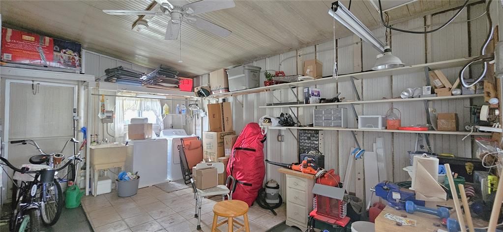Storage/Utility room includes rear & front entry, windows, electricity, ceiling fan, washer/dryer, shelves, workbench, electric water heater, washer, dryer, utility sink