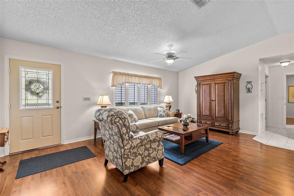 Notice the beautiful laminate floors, high ceilings and plantation shutters.  Primary en-suite through hallway on right of photo.