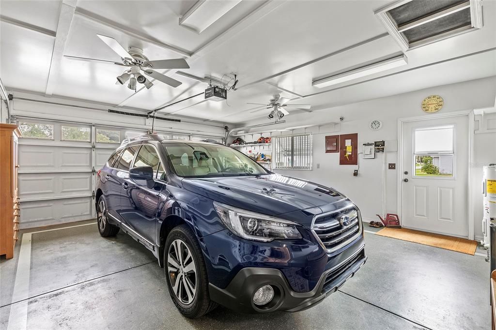 Two car garage with utility door.  Sliding screen door over garage door, two ceiling fans.