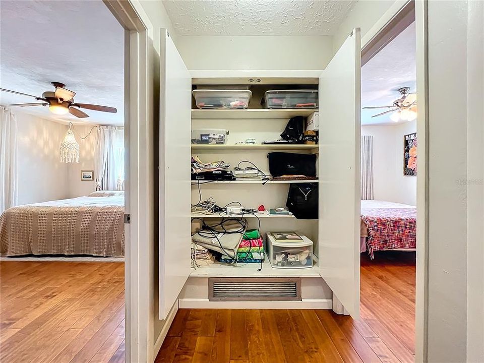 Large closet in between primary and guest bedrooms has wood shleves
