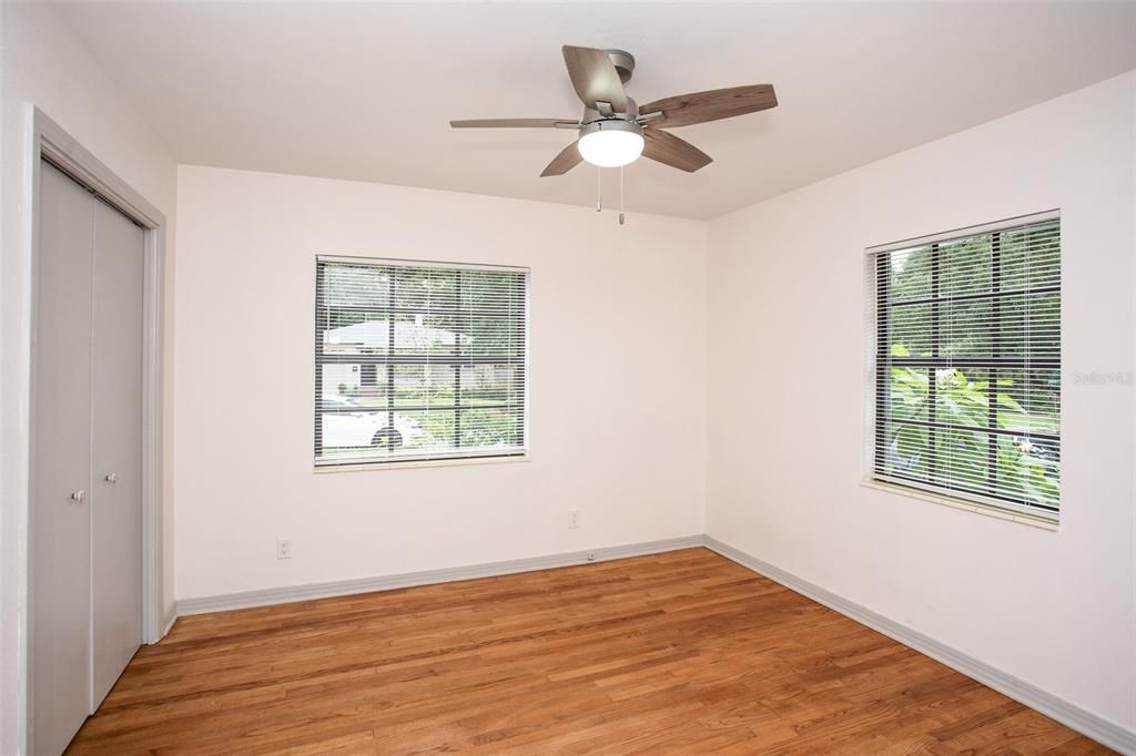 The primary bedroom features oak wood floors, a ceiling fan and a built-in closet.