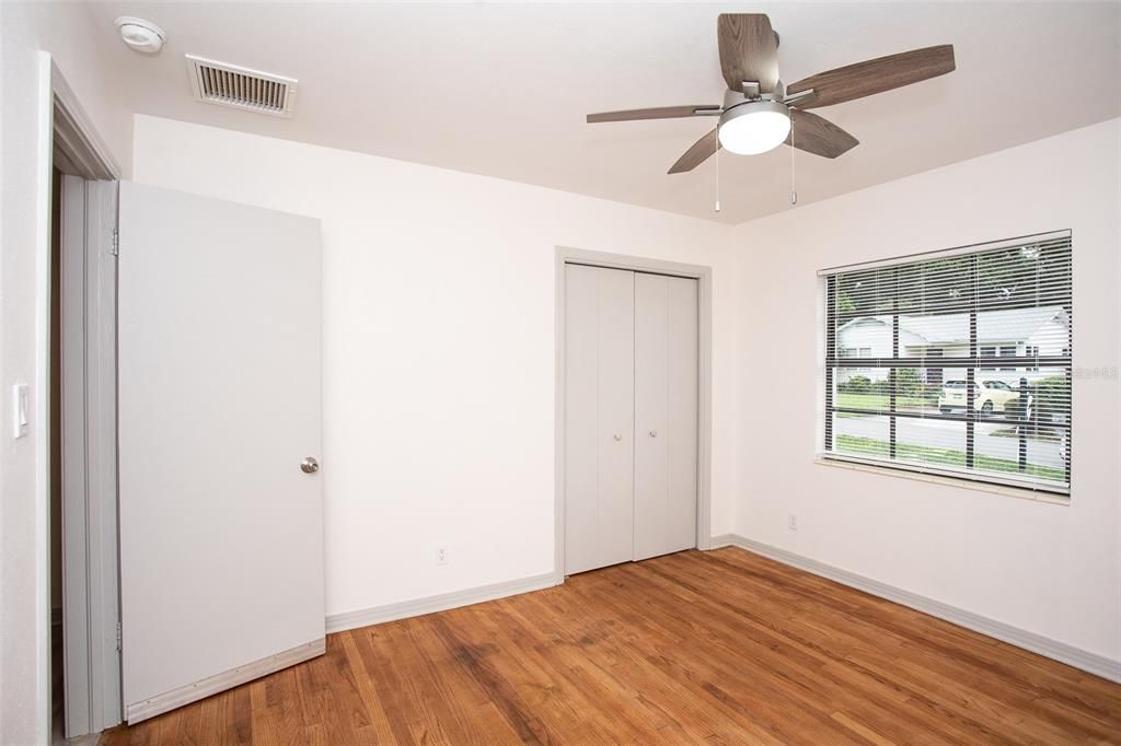 The primary bedroom features oak wood floors, a ceiling fan and a built-in closet.