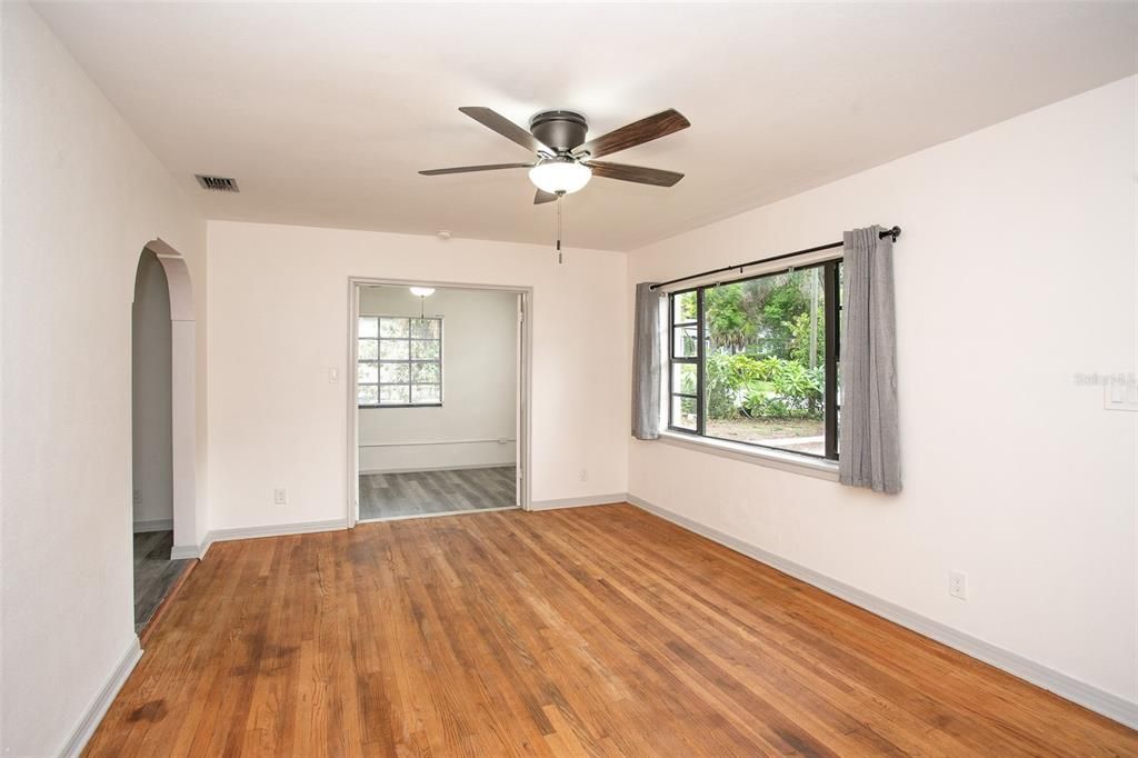 The living room has a ceiling fan and is open to the sun room, with French doors. It's ideal for a home office, gameroom or sitting room.