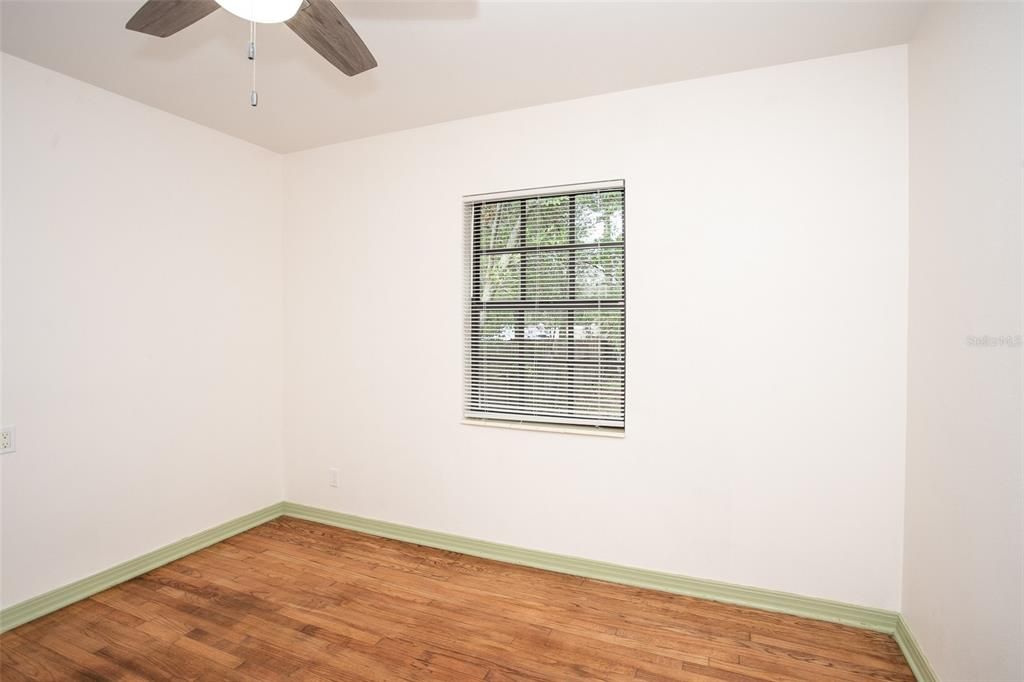 The bedroom 2 features oak wood floors, a ceiling fan and a built-in closet.