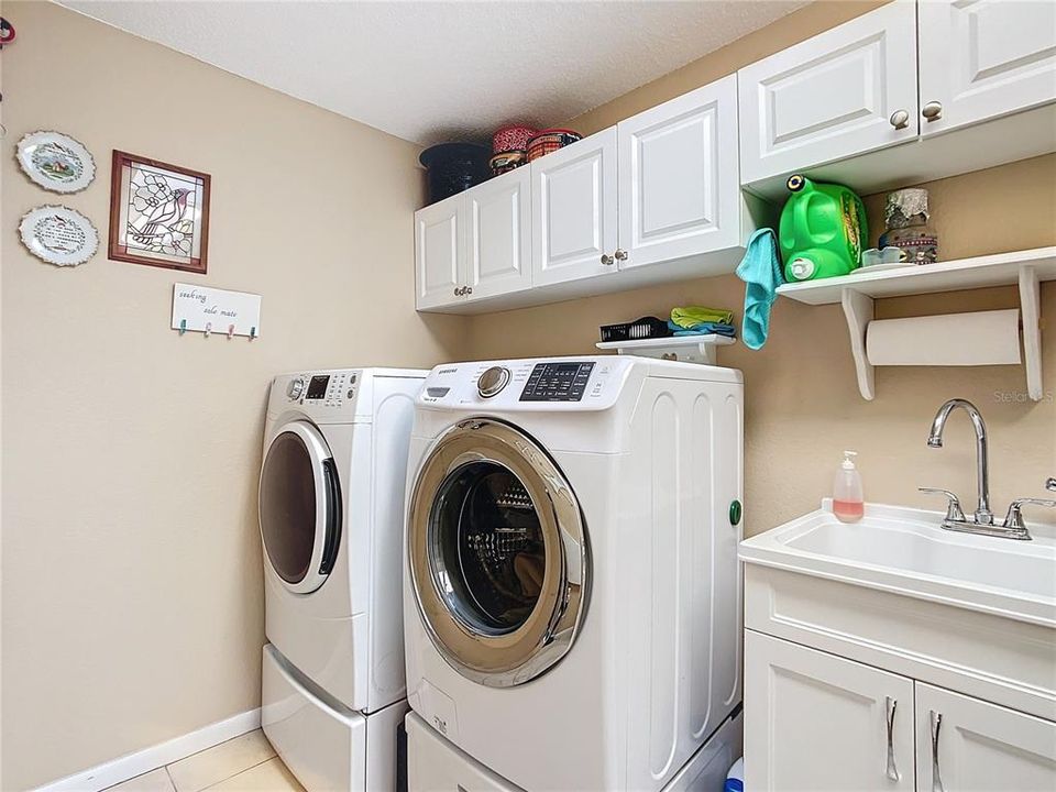 The laundry room is quite spacious the washer, dryer and pedestal will be staying with the home. There are also cabinets for storage and a sink. The room also has a sky light and opens out to the garage.