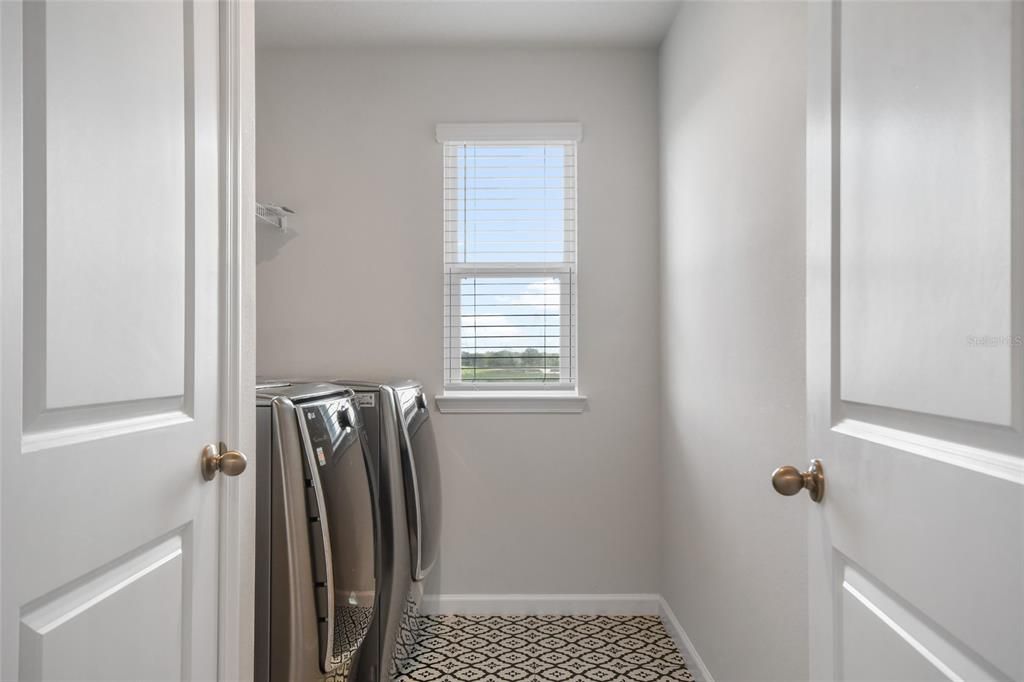 Cheerful and conveniently located laundry room on the second level, where needed most that is complete with a washer and dryer and a window.