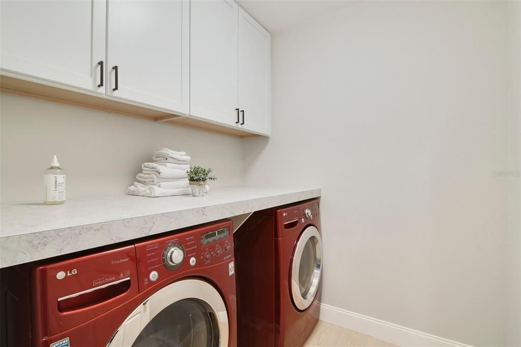 Well appointed laundry room complete with built-in cabinetry and a folding counter!