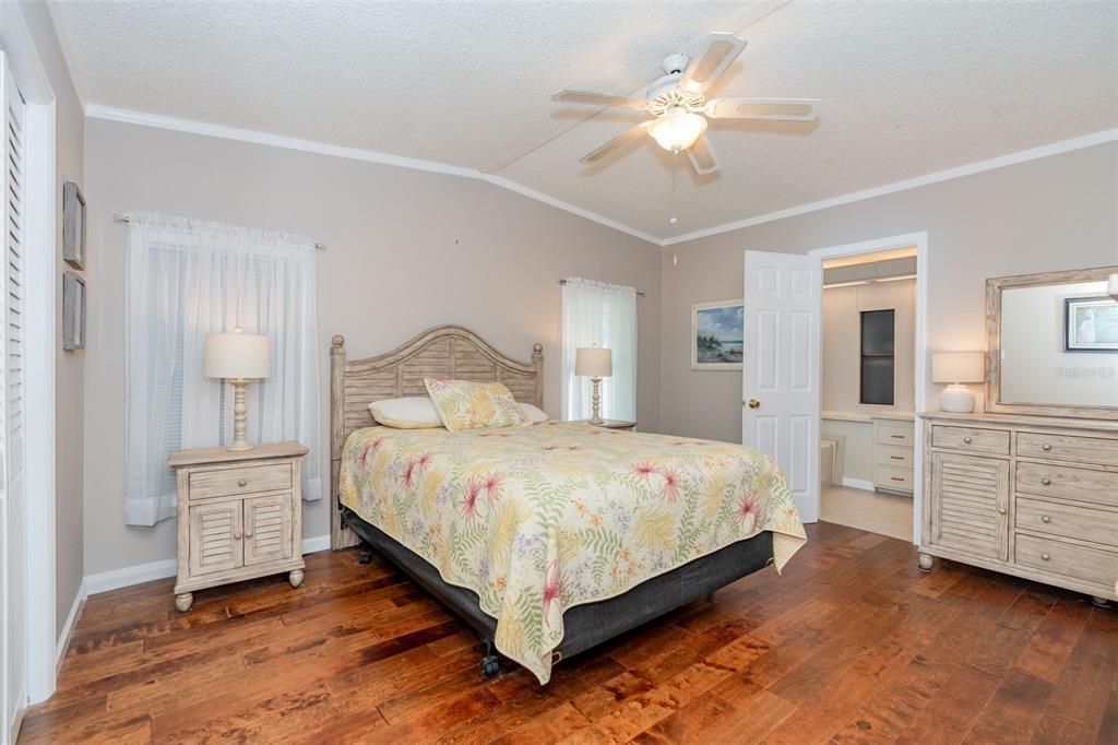 Primary bedroom has walk-in closet, ceiling fan and stunning engineered hardwood flooring at 6339 Partridge Ave. Englewood FL 34224