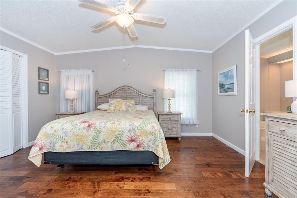 Primary bedroom has walk-in closet, ceiling fan and stunning engineered hardwood flooring at 6339 Partridge Ave. Englewood FL 34224