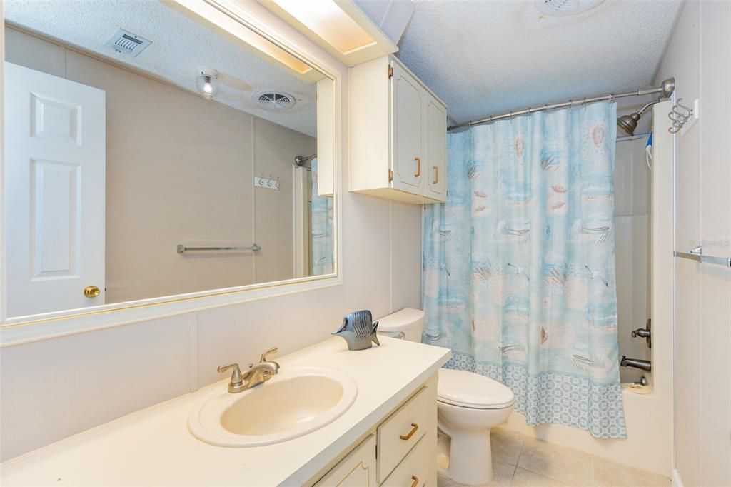 Guest bathroom, tub-shower combo, tile flooring Guest bedroom with a walk-in closet and standard closet, ceiling fan and beautiful flooring at 6339 Partridge Ave. Englewood FL 34224