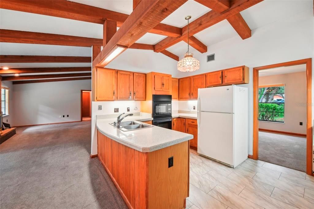 The kitchen updates have begun with the tile floors and countertops and the comfortable space is open to a casual dining area with OVERSIZED SLIDING GLASS DOORS to access the lanai and the family room beyond all topped with gorgeous WOOD BEAM accents!