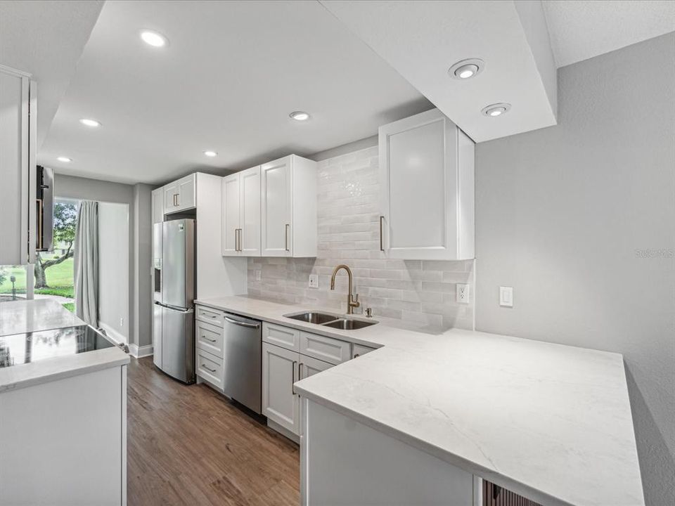 Kitchen with upgraded lighting, wood cabinetry and quartz countertops and breakfast counter