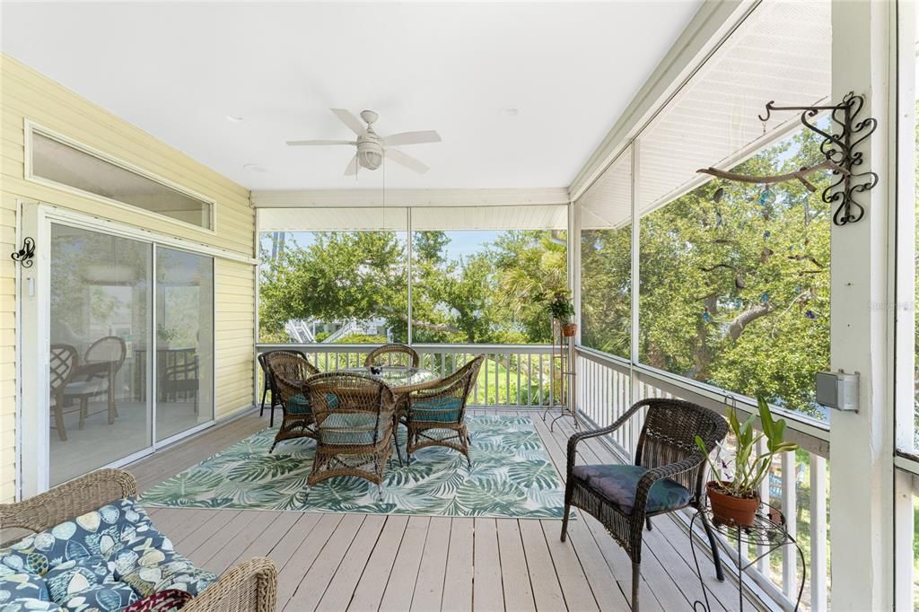 The screen porch features wood deck and ceiling fan.