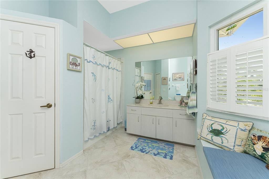 The guest bathroom has a combo tub / shower, tray ceiling with a ceiling fan, wall closet, and tiled flooring.