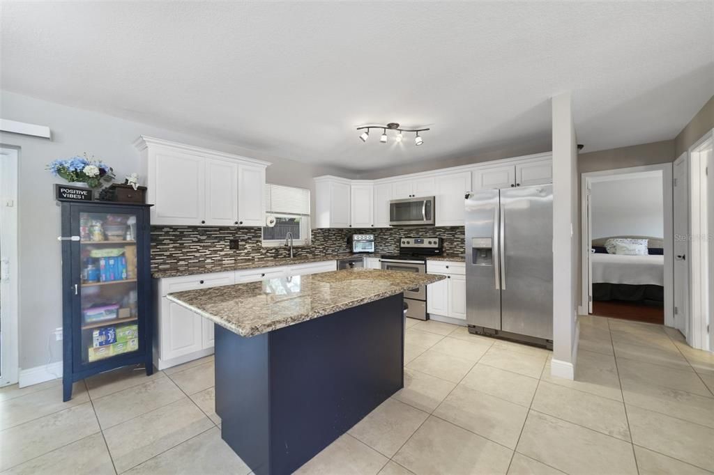 The remodeled/upgraded kitchen offers the family chef a comfortable space surrounded by beautiful solid wood cabinets (freshly painted 2023), STAINLESS STEEL APPLIANCES, tiled backsplash, GRANITE COUNTERS and large island with BREAKFAST BAR seating for casual dining or entertaining!