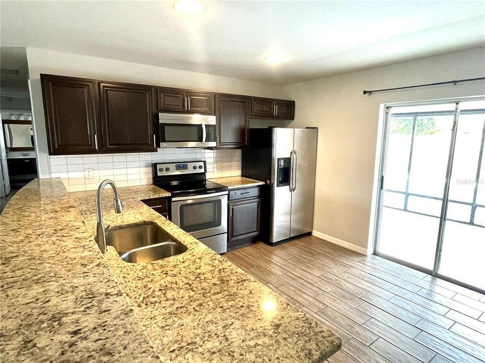 View of kitchen from door to garage. Glass sliders on right open to screen room and pool.