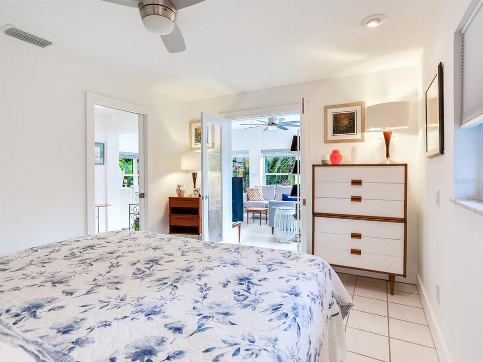 Primary Bedroom - 1st floor - with French Doors that lead to the spacious Sunroom, with garden view in the background.