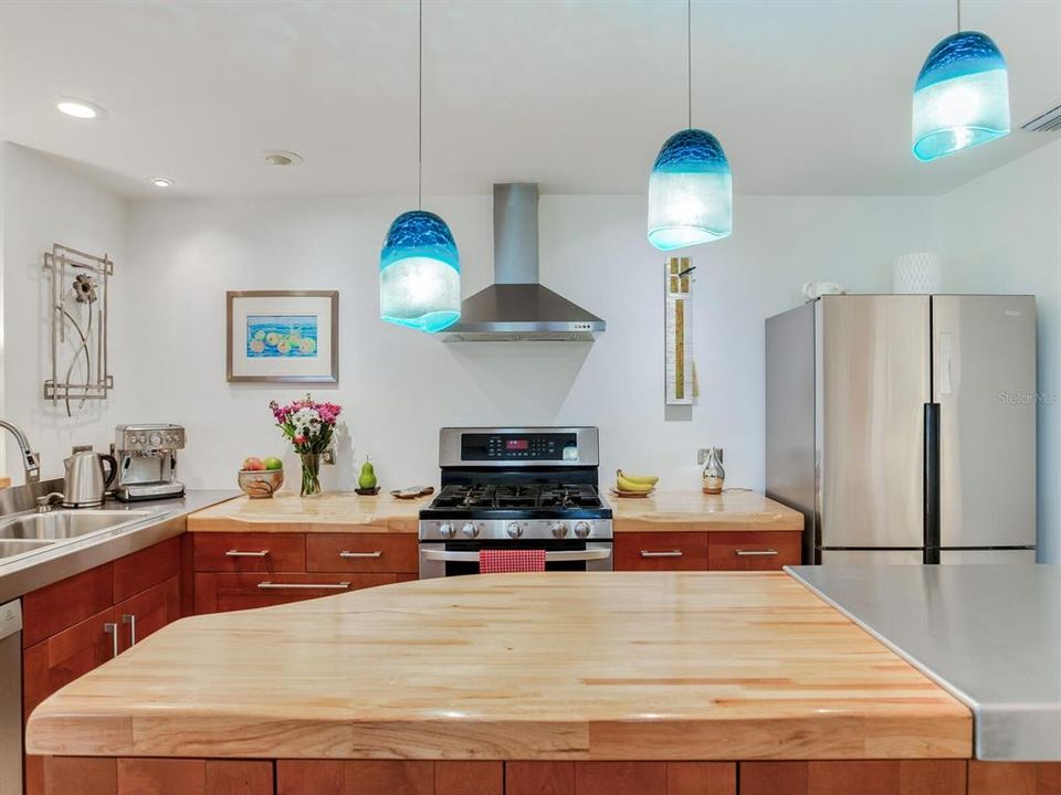 Stainless and wood counter tops - dimmable pendant and recessed lighting - clean and interesting. Not a cookie cutter kitchen. This one has some character.