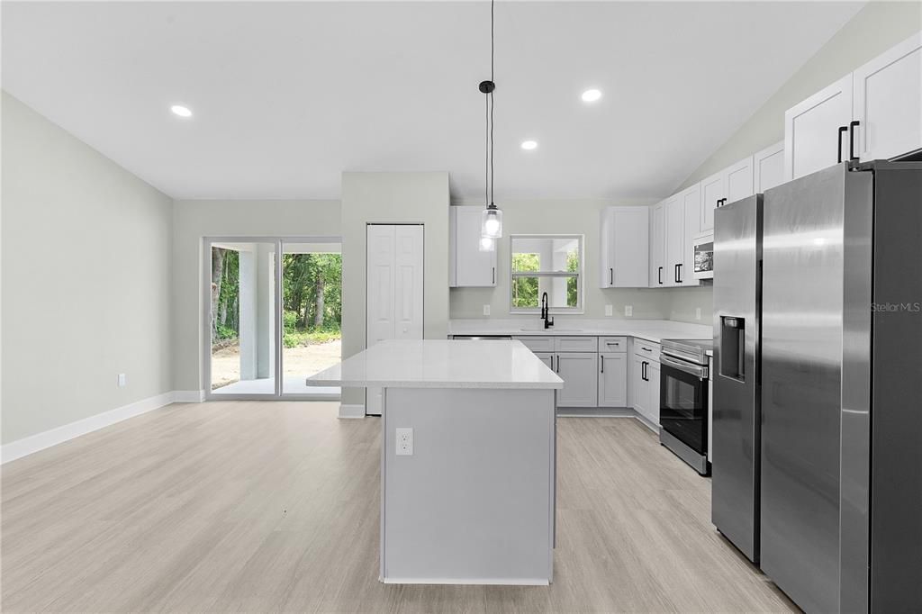 Kitchen with Samsung appliances, island with breakfast bar, and pantry closet