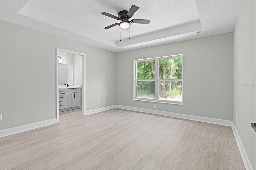 Primary bedroom with tray ceiling and ensuite bath