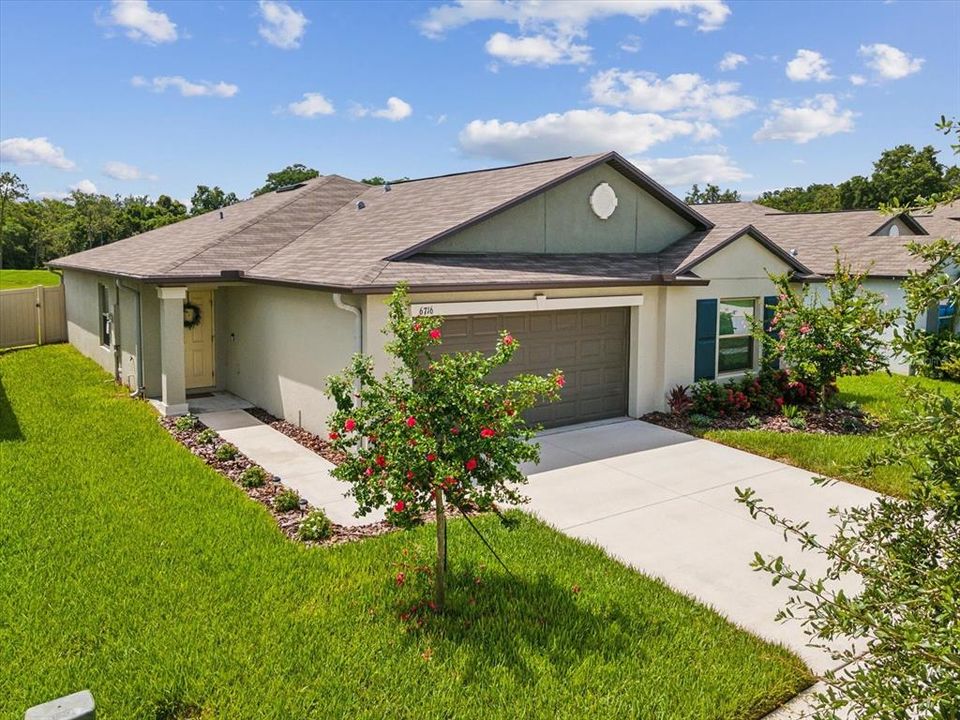 Front exterior of the home with nice landscaping, shutters, and accent front door color