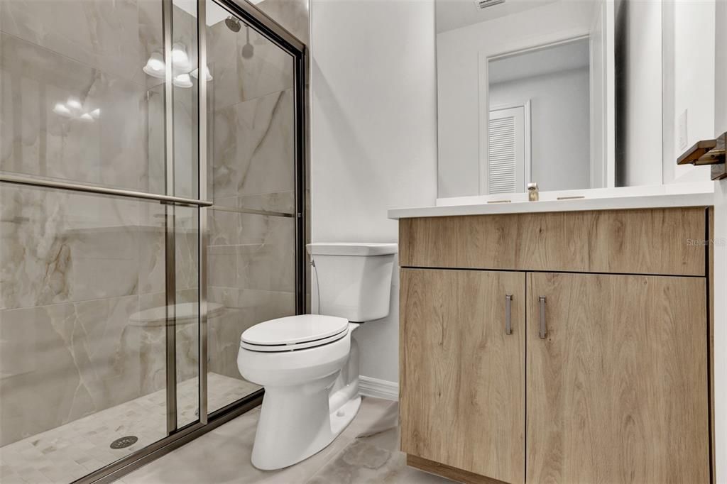 Full bathroom with walk-in shower, quartz countertops, and soft-close cabinets