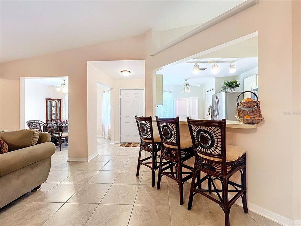 View of the breakfast bar and pass through from the kitchen and dining room/flex room by the front door.